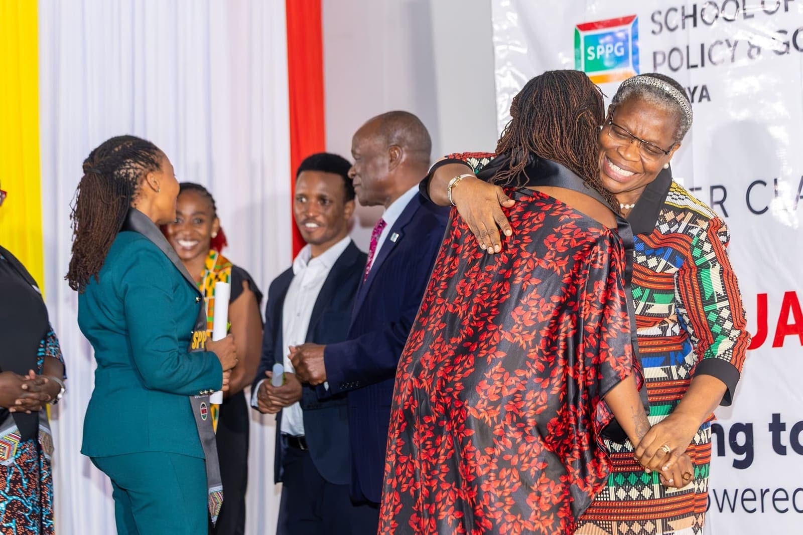 A graduate is embraced on stage